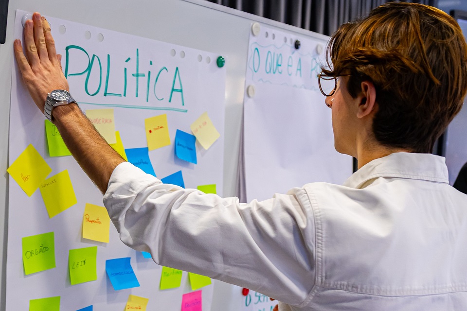 Foto de jovem e post-its com mensagens sobre política durante uma atividade no Bootcamp